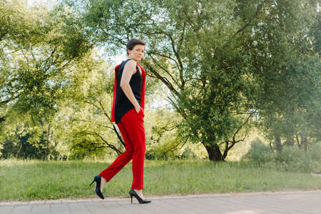 Portrait of a girl in a red suit standing in the alley of the parkの写真素材