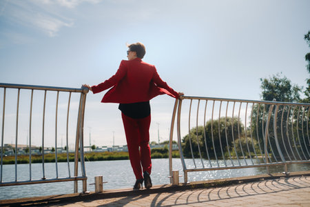 A girl in a red suit stands on a pier near the lakeの写真素材