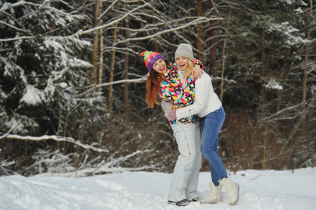 Two girls in the winter forest emotionally hug and smile.Happy women hug and Express joy
