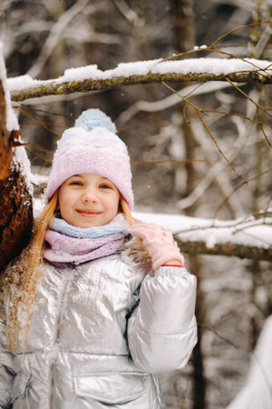a little girl in a silver jacket in winter goes outside in winter.の写真素材