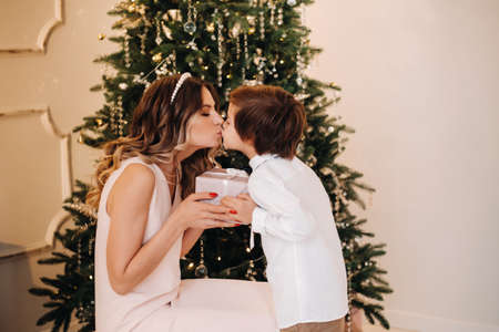 Mom gives her son a Christmas present near the Christmas tree.Happy family.の写真素材