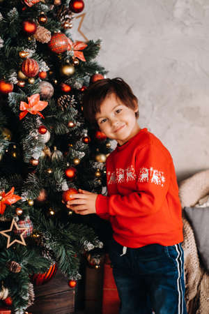 portrait of a smiling boy standing at the Christmas tree at home.の写真素材