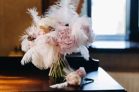The bride's wedding bouquet of roses decorated with white feathers and a boutonniere.の写真素材