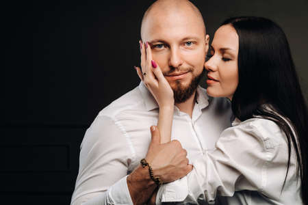 A man and a woman in white shirts on a black background. A couple in love in the studio interior.