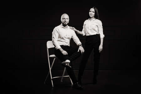 A man and a woman in white shirts on a black background.A couple in love in the studio interior.black and white photo.の写真素材