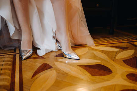 Close-up of women's shoes and the hem of a wedding dress. The bride's foot in a silver slipper.の写真素材