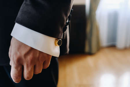 Close-up of a man's hands in a black formal suit with cuffs.の写真素材