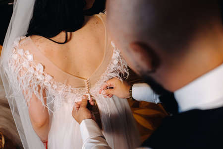 Morning of the bride. The groom helps to dress the bride in a wedding dress.の写真素材