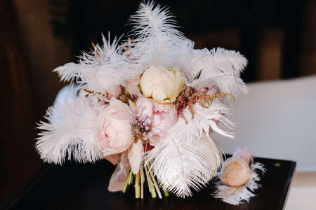 The bride's wedding bouquet of roses decorated with white feathers and a boutonniere.の写真素材