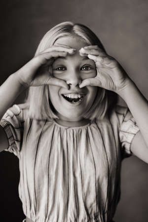 A happy child, a little girl in a gray T-shirt on a beige background.black and white photoの写真素材