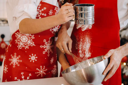 Close-up of hands pouring flour into a container for stirring dough.の写真素材