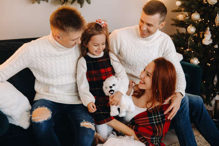 Close-up portrait of a happy family sitting on a sofa near a Christmas tree celebrating a holiday.の写真素材