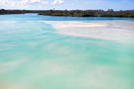 A view from a height of a Tropical beach and waves breaking on a tropical golden sandy beach. The sea waves gently wind along the beautiful sandy beach.の写真素材