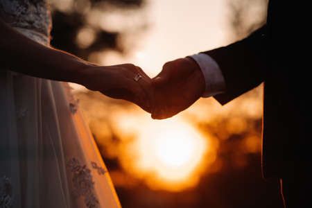 The concept of love and Valentine's Day. Close-up of the hands of a couple holding hands during sunset.の写真素材