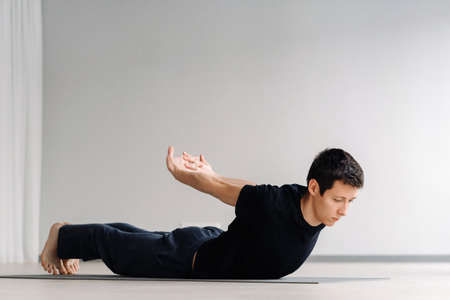 A man in a black T-shirt trains lying down doing stretches in the gym.の写真素材
