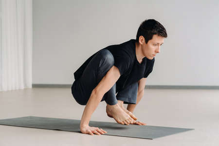A man in a black T-shirt trains lying down doing stretches in the gym.の写真素材