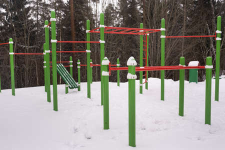 An empty playground with metal bars in a winter forest for children and adults. Health benefits