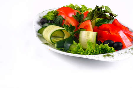 Delicious vegetable salad of tomatoes and cucumbers with olives on a plate on an isolated background.の写真素材