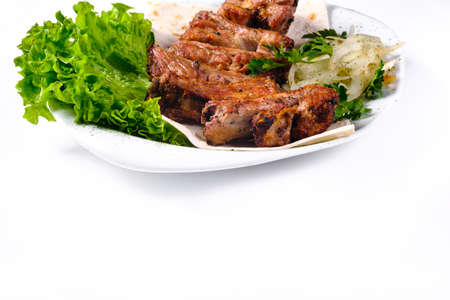 Meat kebab on ribs on lavash with onions and cabbage on a white plate, on an isolated white background.の写真素材