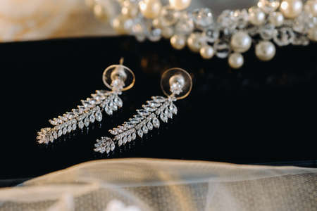 The wedding day. Wedding earrings on the table. Morning of the bride, jewelry accessories.の写真素材