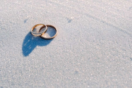 A pair of gold wedding rings in the snow.Two wedding rings.の写真素材