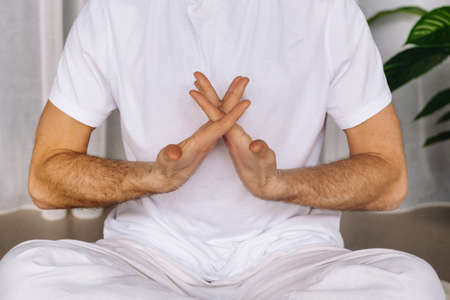 a man in white sportswear is doing yoga with a fitness room. the concept of a healthy lifestyle.の写真素材