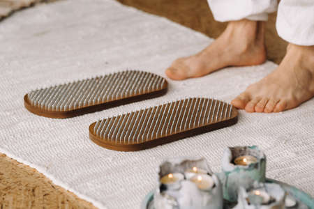 The man's feet are next to boards with nails. yoga classes.