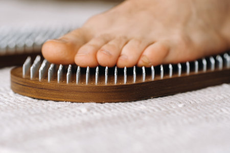 The man's feet are next to boards with nails. yoga classes.