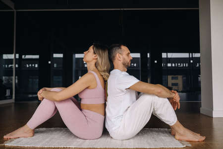 a woman and a man are engaged in pair gymnastics yoga in the gym.の写真素材