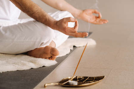 Close-up of a man in white sportswear doing yoga in a fitness room with a balgovon. the concept of a...