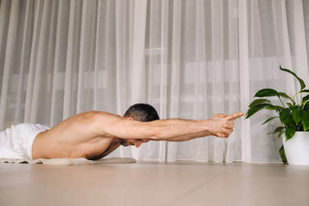 a man with a bare torso does yoga in a fitness room. the concept of a healthy lifestyle.