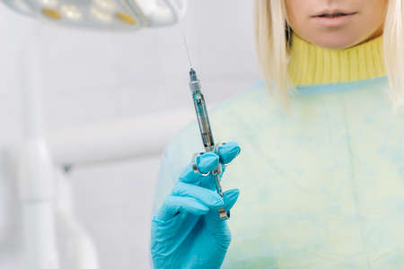 The dentist holds an injection syringe for the patient in the office.の写真素材