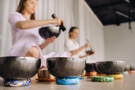 Two female yoga teachers play on Tibetan bowls in the gym during a yoga retreat.の写真素材