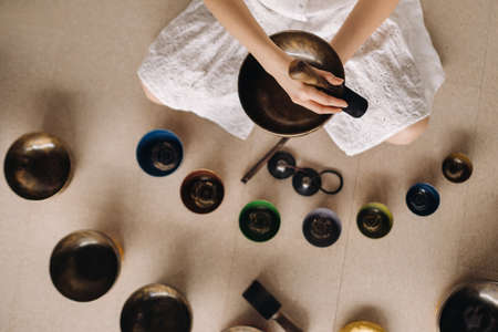 Close-up of a Tibetan singing bowl in your hands - Translation of mantras: transform your impure body, speech and mind into a pure exalted body, speech and mind of a Buddha.の写真素材