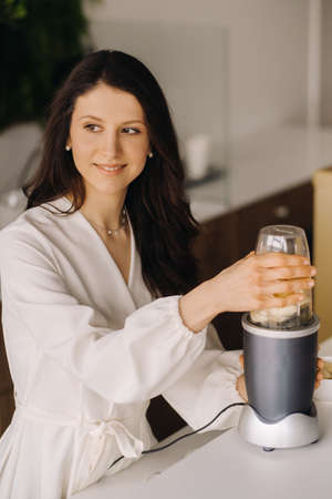 a girl makes a detox cocktail of fruit in the kitchen. Diet for weight loss.の写真素材