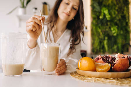 A healthy happy woman made a fruit cocktail standing in the kitchen at home.Healthy eating.