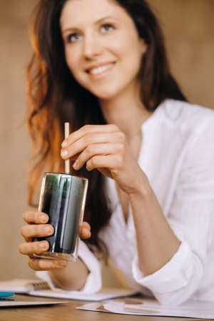 A young freelance woman with a cocktail in her hands at her workplace at work.の写真素材