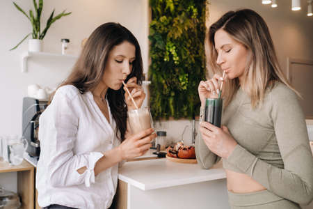 Two sporty-looking girls with cocktails in their hands discuss healthy eating and dietの写真素材