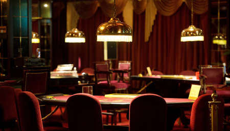 An empty blackjack table in a casino in red tones.