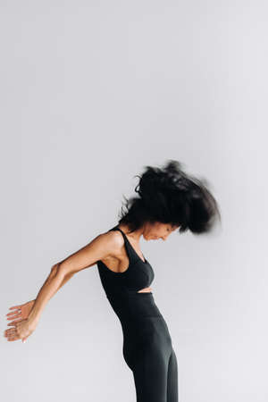 A blurry silhouette of a woman in black sportswear is engaged in dynamic kali meditation in the yoga hall.の写真素材