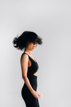 A blurry silhouette of a woman in black sportswear is engaged in dynamic kali meditation in the yoga hall.の写真素材