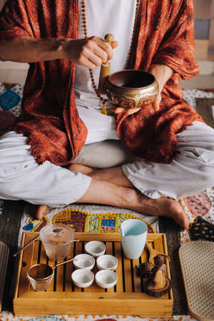 Tibetan singing bowl in the hands of a man during a tea ceremony.の写真素材
