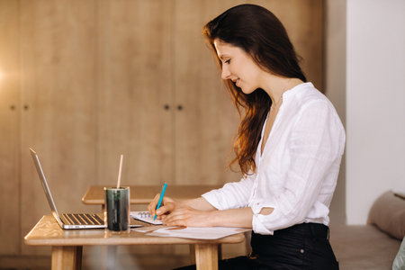 The girl is sitting at a desk in the office and working.の写真素材
