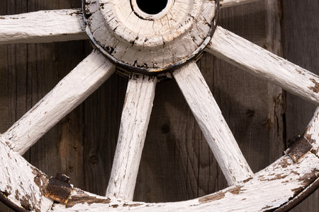 An old wooden carriage wheel hanging on the barn wall.の写真素材