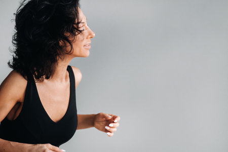 A woman in black sportswear is engaged in dynamic kali meditation in the Yoga hall.
