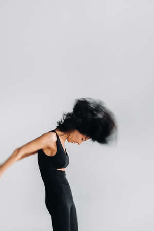 A blurry silhouette of a woman in black sportswear is engaged in dynamic kali meditation in the yoga...