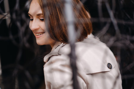 A happy stylish girl In a gray coat is sitting outside in an armchair.の写真素材