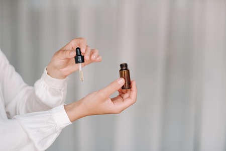 Close-up of a Woman's hands applying essential oil on her wrist indoors.の写真素材