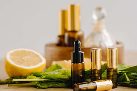 Essential oil in bottles with lemon and mint fragrance lying on a wooden surface.の写真素材
