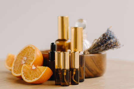 Essential oil in bottles with the aroma of orange and lavender lying on a wooden surface.の写真素材